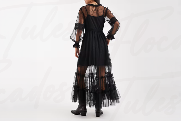 Mulher usando vestido preto com detalhes em tule transparente e botas pretas